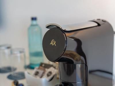 Close-up van een koffiemachine met capsules en een waterfles op een aanrecht.