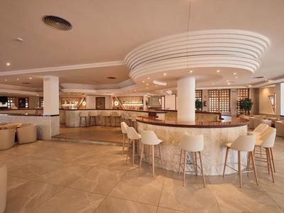 Moderner Hotelbar-Bereich mit geschwungener Theke und bequemen Sitzgelegenheiten in warmen Tönen.
