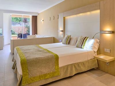 Modernes Hotelzimmer mit zwei Einzelbetten, Holzmöbeln und Balkon mit Blick ins Grüne.