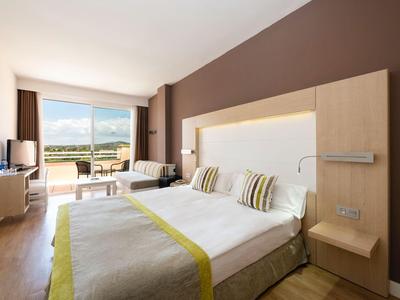 Modernes Hotelzimmer mit großem Bett, Sitzbereich und Balkon mit Blick auf die Berge.