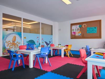 Bunter Kinderspielraum mit kleinen Tischen, Stühlen und spielerischen Meereswandbildern im Hotel.
