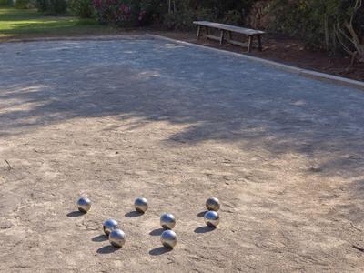 Ein Sandplatz mit fünf silbernen Kugeln und einem kleinen Zielkugel in der Ecke.