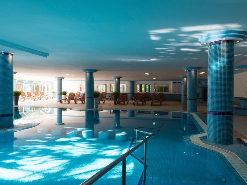 Piscina coperta con colonne e luce solare che illumina l'acqua blu.