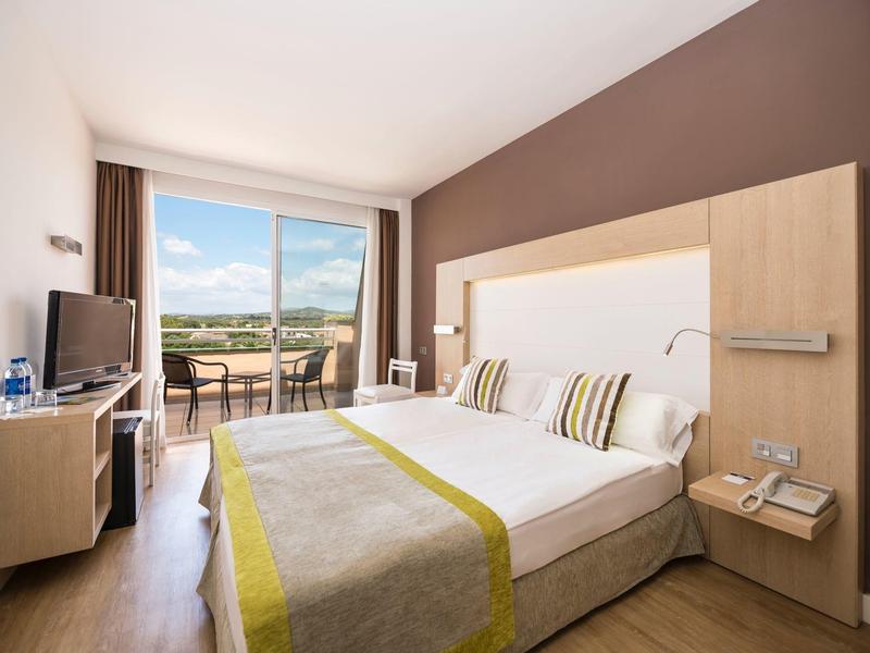 Camera d'hotel moderna con letto matrimoniale, balcone con vista e interno luminoso e accogliente.