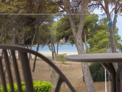 Vista da una terrazza con sedia e tavolo su una spiaggia boschiva con il mare sullo sfondo.