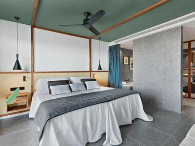 Camera d'hotel moderna con letto matrimoniale, pavimento grigio e ventilatore a soffitto.