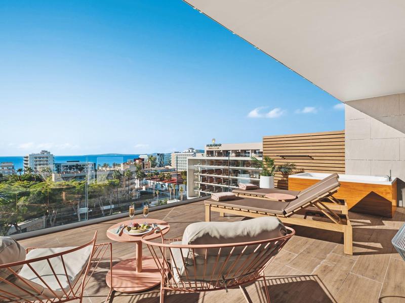 Moderna terrazza dell'hotel con sedie, lettini e vista sul mare in una giornata di sole.