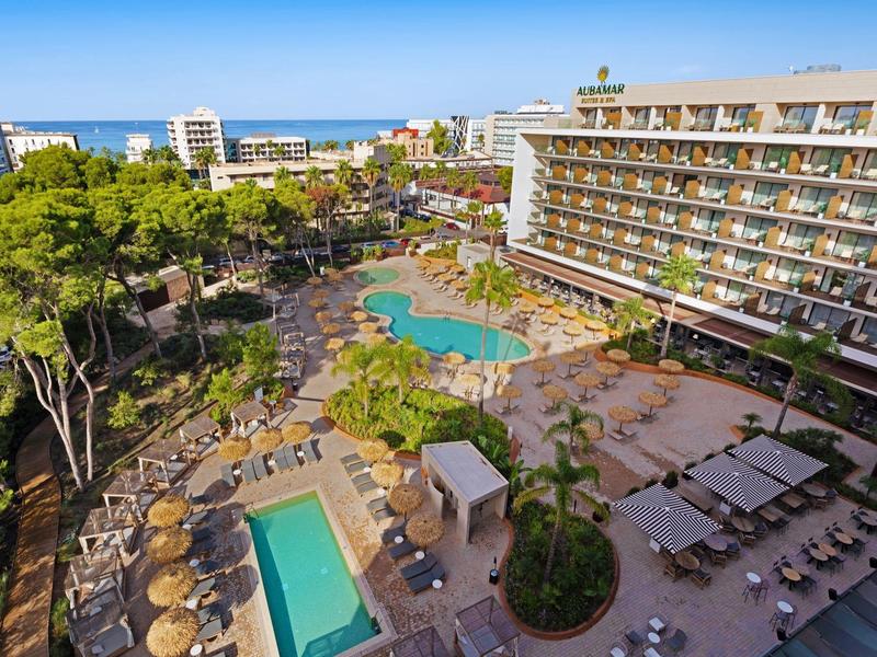Complesso alberghiero con due piscine, lettini e vista mare sotto un cielo sereno.