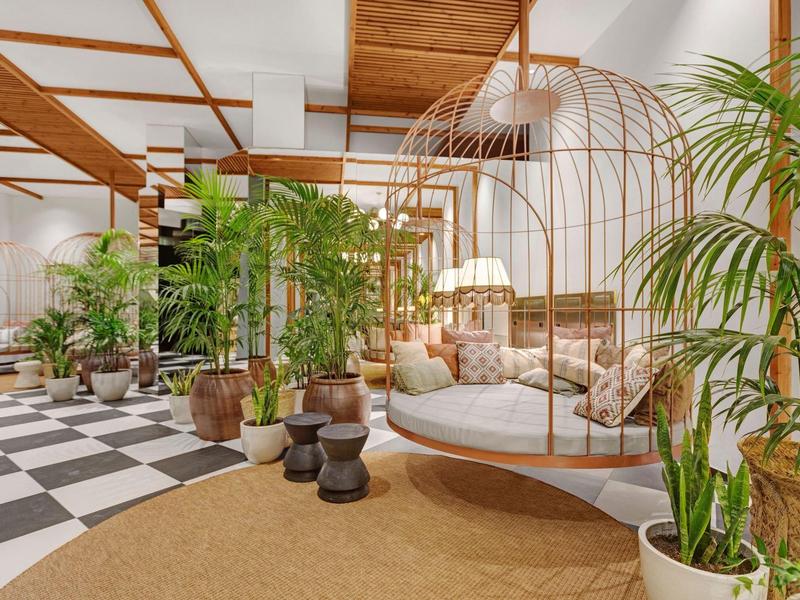 Un soggiorno luminoso con area salotto sospesa, piante verdi e soffitto in legno.