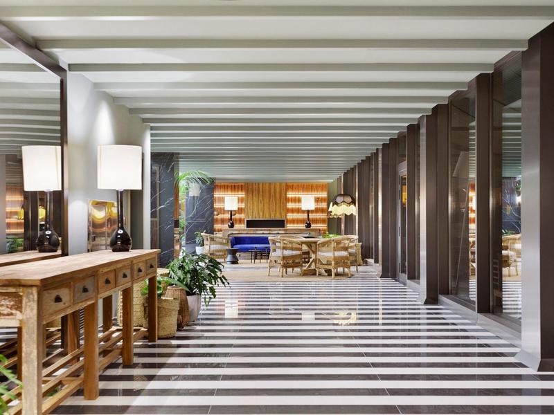 Luminosa hall d'hotel con pavimento a strisce in marmo e arredamento moderno.