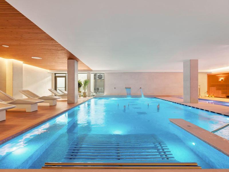 Piscina interna con lettini e illuminazione al soffitto in una spa dell'hotel.