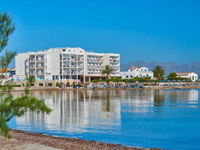 Grande hotel bianco sulla riva calma con cielo azzurro limpido e acqua.