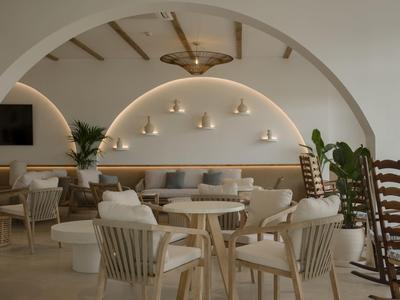 Locale pranzo di un hotel moderno e luminoso con pareti curve, mobili in legno e illuminazione d'atmosfera.
