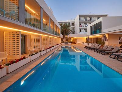 Piscina esterna moderna con lettini e illuminazione in un hotel al crepuscolo