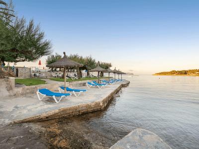 Sdraio al bordo dell'acqua con vista su una baia calma sotto un cielo sereno.