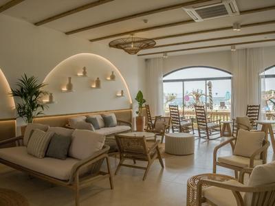 Světlý, moderní hotelový salonek s pohodlnými křesly a výhledem na terasu.