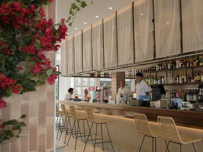 Moderní hotelový bar s dřevěnými stoličkami a květinami v popředí.