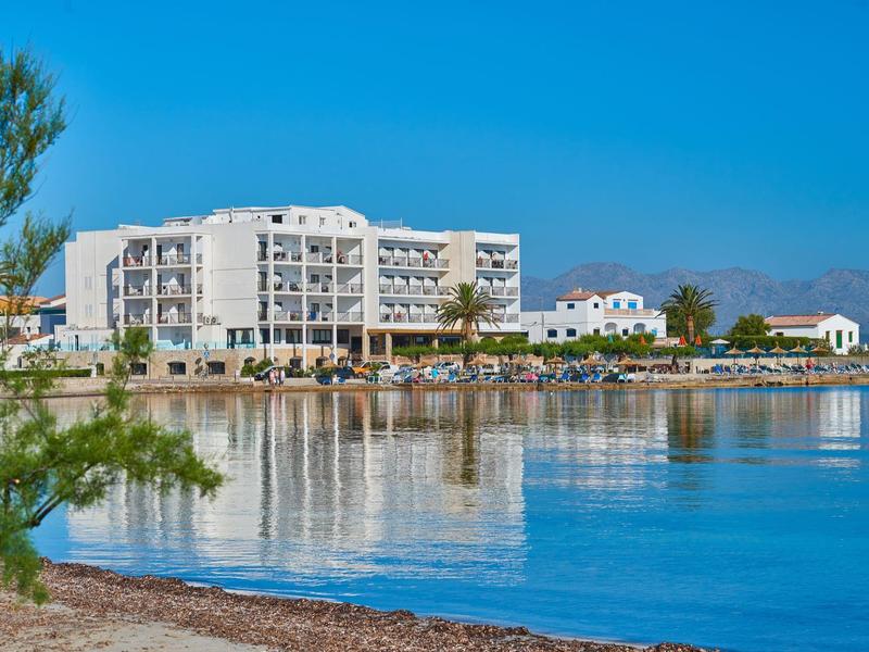 Grande hotel bianco sulla riva calma con cielo azzurro limpido e acqua.