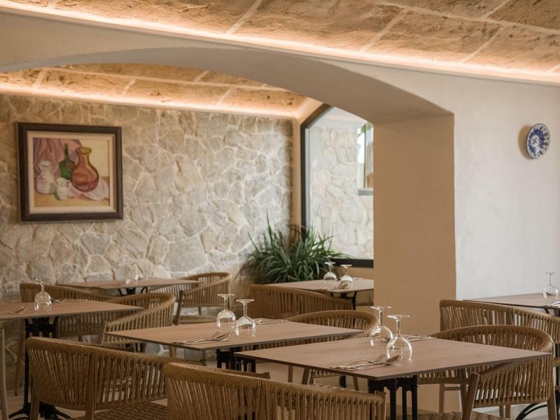 Accogliente sala da pranzo con tavoli in legno, sedie e pareti in pietra decorative.