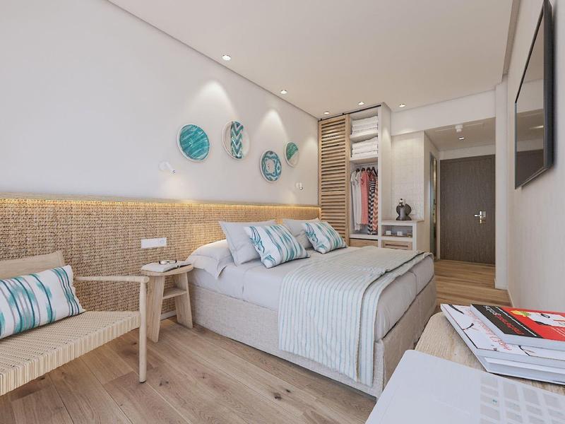 Camera da letto moderna con letto grande, sedia in legno e pareti decorative in toni chiari.