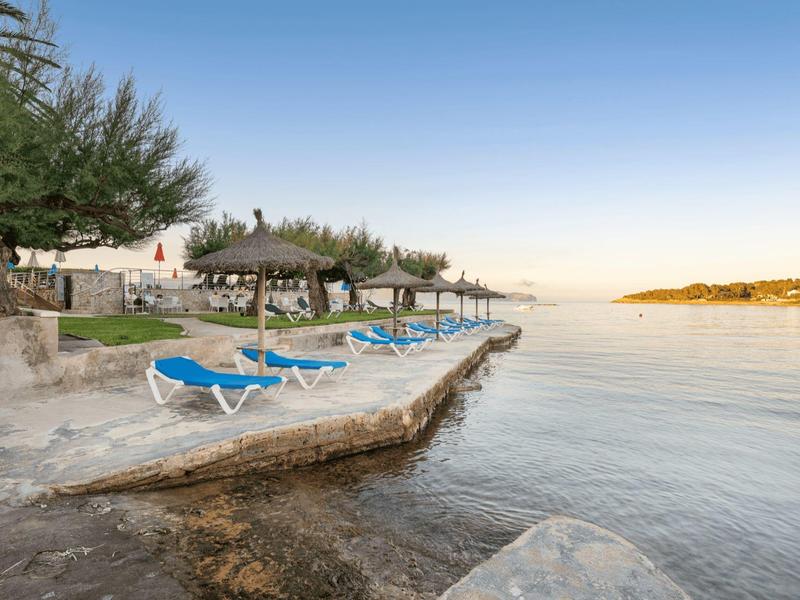 Sdraio al bordo dell'acqua con vista su una baia calma sotto un cielo sereno.