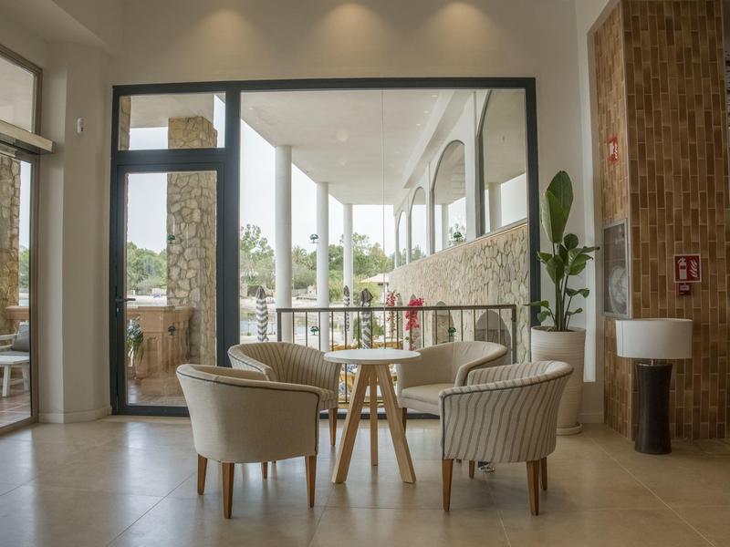 Area salotto accogliente con poltrone rotonde e tavolo in legno accanto a grandi finestre con vista esterna.