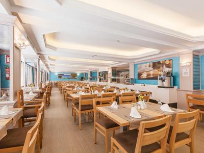 Large bright dining room with wooden tables and chairs, nicely decorated and set up.