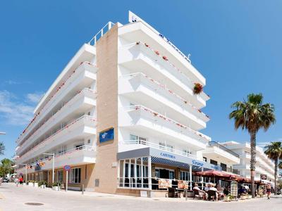 Modern multi-story hotel building with balconies and terrace under blue sky