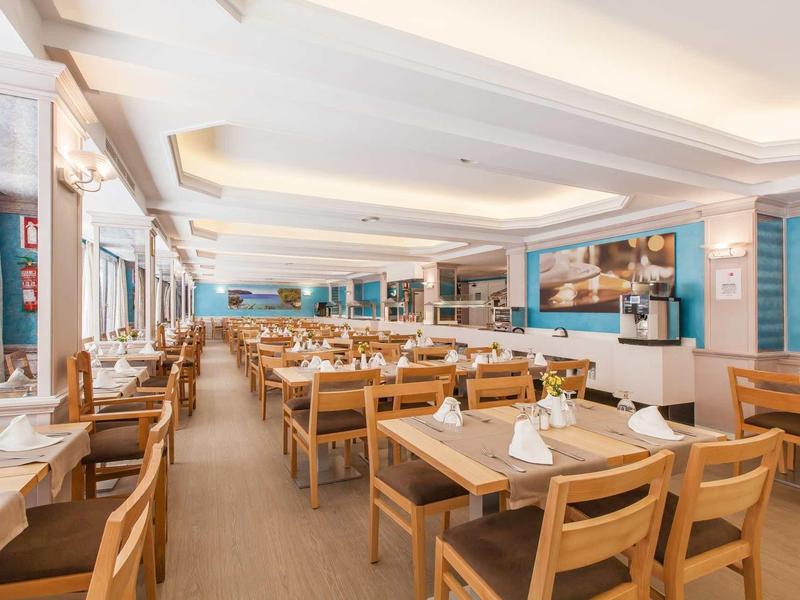 Large bright dining room with wooden tables and chairs, nicely decorated and set up.