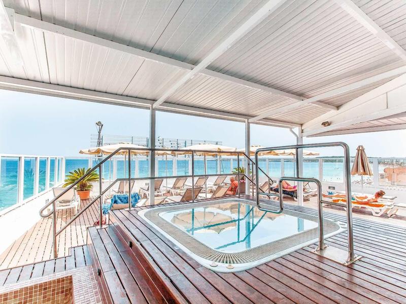 Hot tub with sea view on a wooden deck under a white sunshade.
