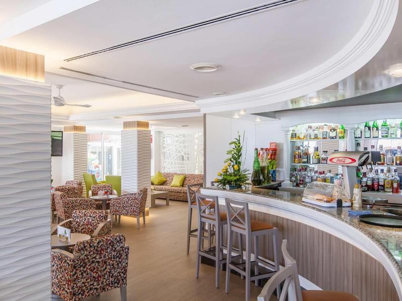 Bright bar area with curved counter, bar stools, and cozy seating areas.