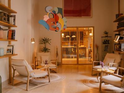 Salon d'hôtel confortable avec étagères en bois, fauteuils et éclairage chaleureux.