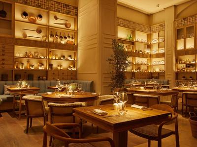 Pohodlná hotelová restaurace s teplým osvětlením a dřevěnými stoly připravenými k večeři.