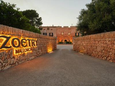 Vstup do Zoetry Mallorca s kamennými zdmi a osvětleným nápisem při soumraku.