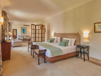 Prostorný hotelový pokoj se dvěma velkými postelemi, posezením a teplým osvětlením.