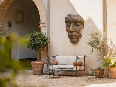 Sezení s pohodlnou lavicí a nástěnnou dekorací ve tvaru obličeje na nádvoří.