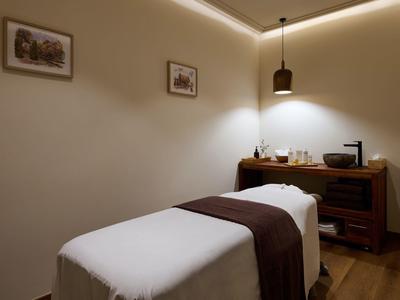 Pohodlný spa pokoj s masážním stolem, měkkým osvětlením a dřevěným nábytkem.