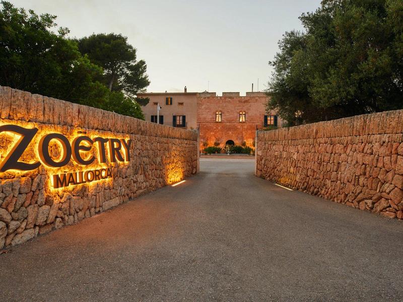 Vstup do Zoetry Mallorca s kamennými zdmi a osvětleným nápisem při soumraku.
