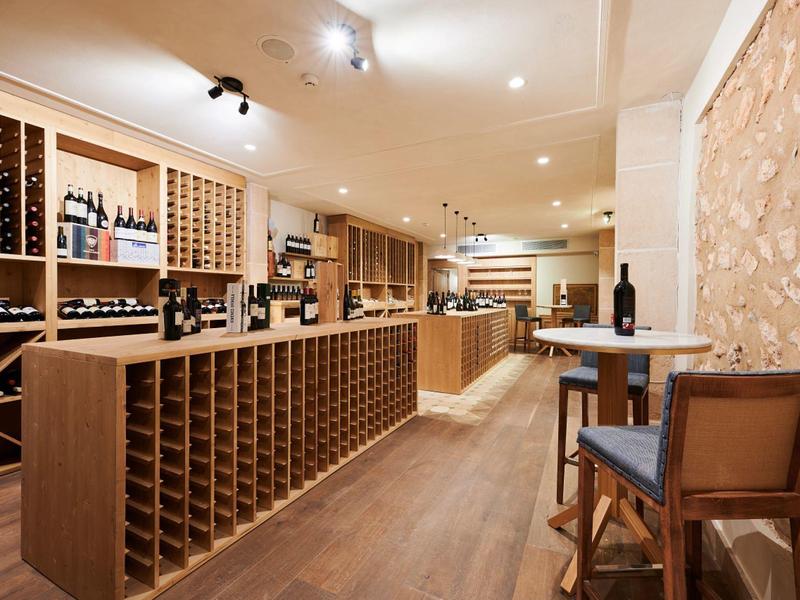 Moderní vinný sklep s dřevěnými regály, stoly a teplým osvětlením.