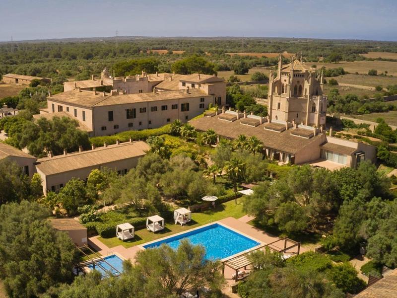 Venkovský hotel s bazénem, obytnými vozy, zahradami a starou kostelní věží.