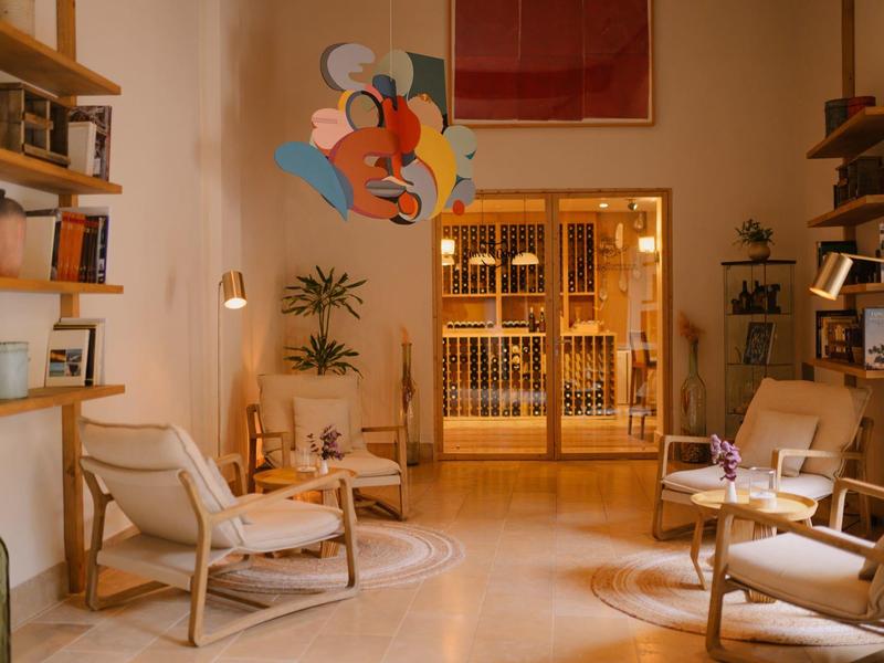 Pohodlný salonek s dřevěnými křesly, policemi, rostlinami a teplým osvětlením v hotelové hale.