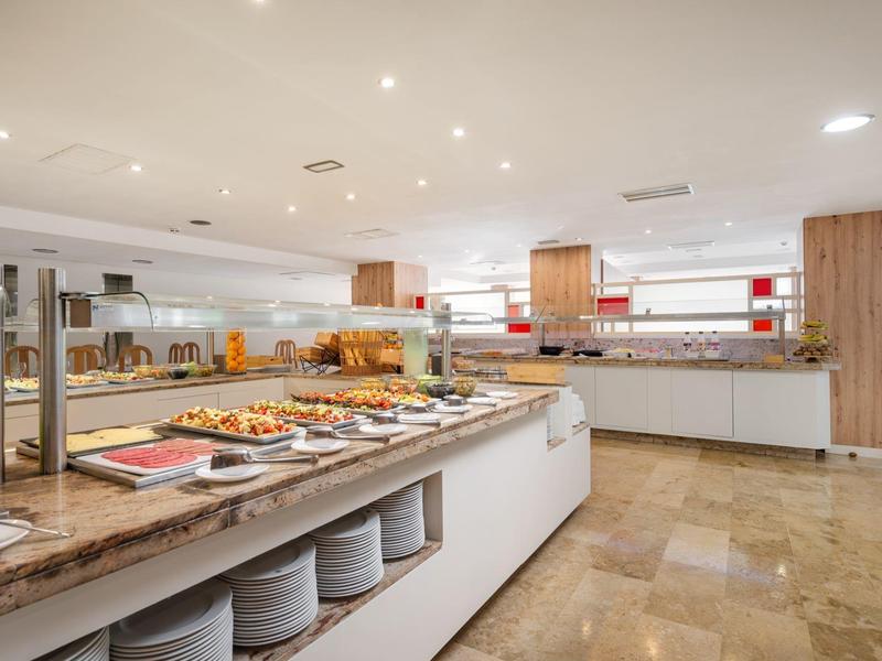 Buffet de hotel luminoso con variedad de alimentos y elementos modernos de madera y mármol.