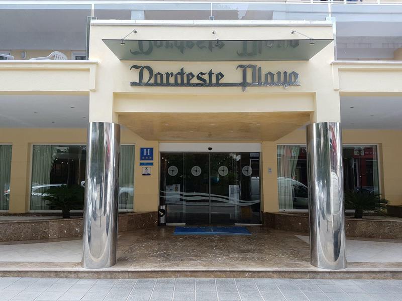 Entrada del hotel Dorchester Plaza con columnas lisas y marquesina de vidrio.