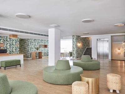 Hall d'hôtel moderne avec sièges verts et mur à motif de tapis.