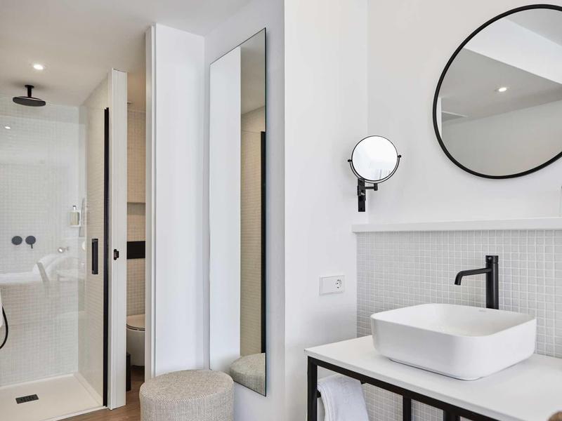 Moderní koupelna se čtvercovým umyvadlem, kulatými zrcadly a sprchovým koutem.