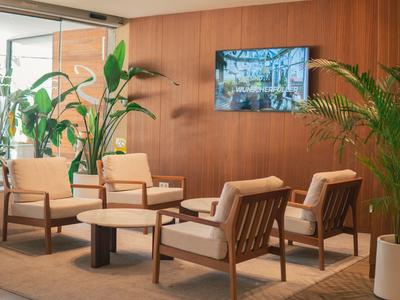 Przytulny salon z drewnianymi panelami, fotelami, roślinami i telewizorem na ścianie.