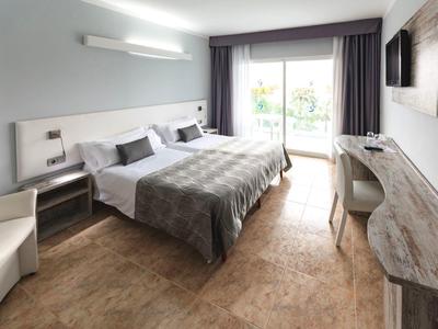 Nowoczesny pokój hotelowy z łóżkiem podwójnym, biurkiem i balkonem z dużą ilością naturalnego światła.