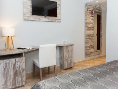 Nowoczesne miejsce do pracy w pokoju hotelowym z krzesłem, biurkiem, telewizorem i drewnianymi akcentami.