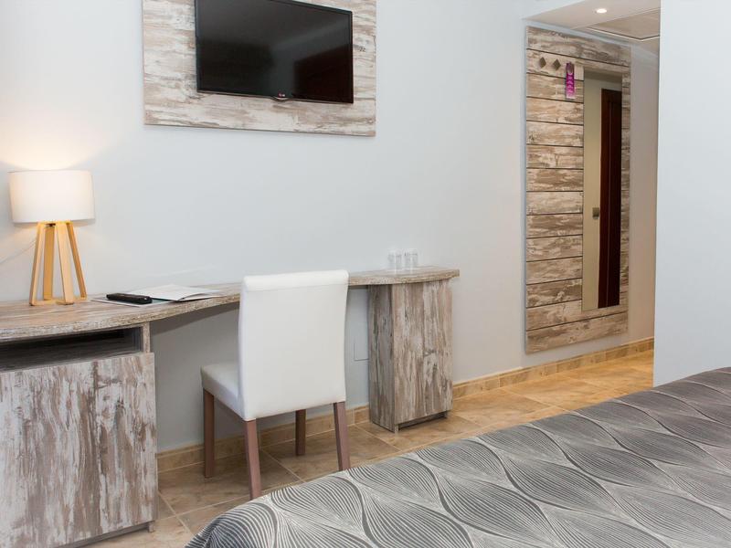 Nowoczesne miejsce do pracy w pokoju hotelowym z krzesłem, biurkiem, telewizorem i drewnianymi akcentami.