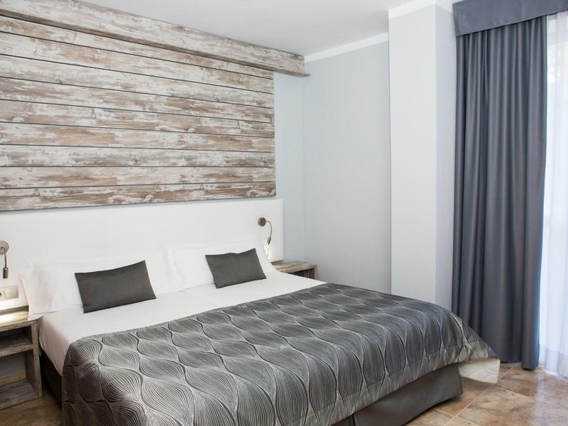 Nowoczesny pokój hotelowy z dużym łóżkiem, drewnianą ścianą i szarymi zasłonami